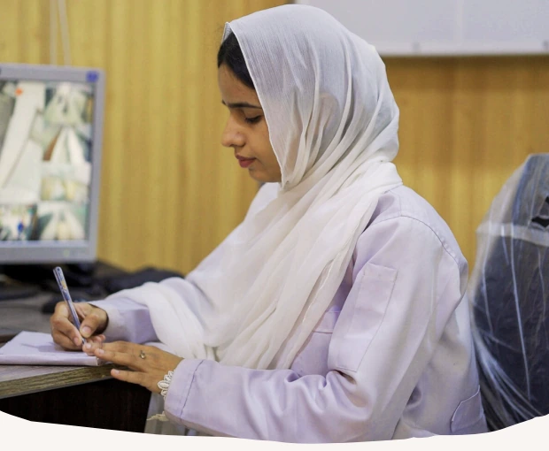Bushra writing notes at the medical clinic in Karachi
