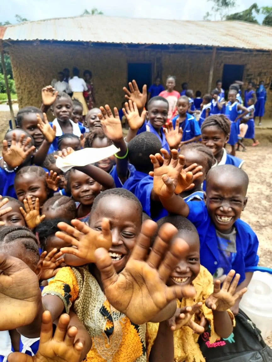 Children waving outside their school, Sierra Leone